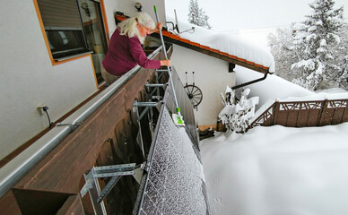 Eine Frau befreit im Winter ein Balkonkraftwerk vom Schnee