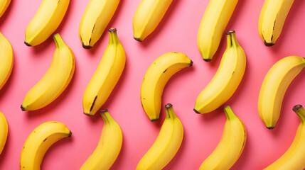 Fresh yellow bananas on a pink background, arranged in a creative pattern. Healthy fruit concept.