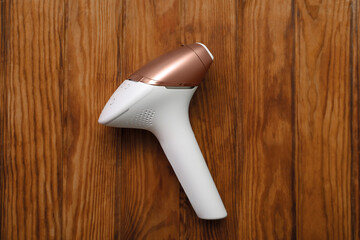 Fototapeta premium Modern photoepilator on brown wooden background