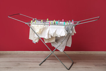 Clean clothes hanging on dryer near red wall