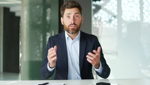 Webcam view. Businessman in a formal suit talking on a video call looking at camera sitting at a workplace in the office. Entrepreneur has a business meeting. Coach speaks remotely at an online course