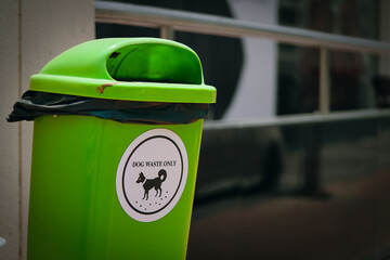 Environmentally conscious solution, this green trash bin with a white sticker to dog waste disposal, highlighting ecological mindfulness and the importance of cleaning up after dogs.