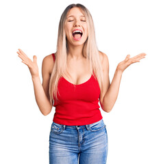 Young beautiful blonde woman wearing casual clothes celebrating mad and crazy for success with arms...
