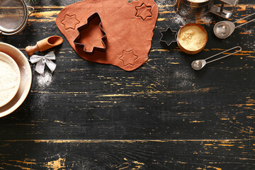 Fresh dough and ingredients for Christmas gingerbread cookies on black wooden background