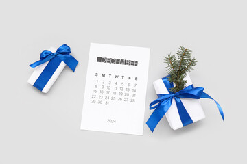Paper calendar for December 2024 with gift boxes on grey background - obrazy, fototapety, plakaty