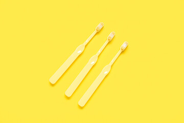 Three toothbrushes on yellow background.