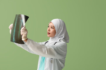 Female Muslim doctor in hijab with x-ray image on green background. World Hijab Day concept