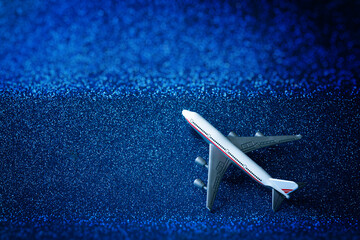 Toy model of a passenger plane - airliner on a sparkling blue background. Simulation of flight in...