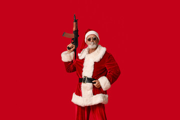 Fototapeta na wymiar Santa Claus in sunglasses with assault rifle on red background