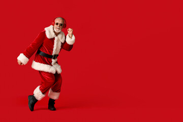 Fototapeta na wymiar Santa Claus in headphones listening music on red background