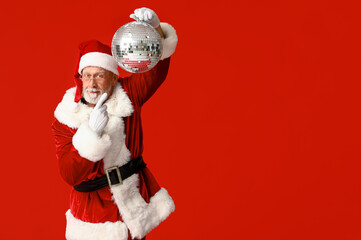 Santa Claus in glasses pointing at disco ball on red background