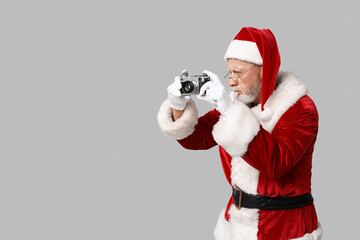 Santa Claus in glasses with camera taking photo on grey background - Powered by Adobe