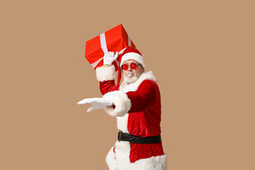Fototapeta na wymiar Santa Claus in sunglasses with gift box on brown background