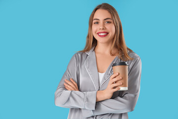 Fototapeta premium Smiling young woman in silk pajamas holding disposable coffee cup, morning routine and relaxation