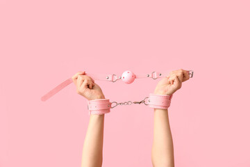 Female hands with sex toys on pink background
