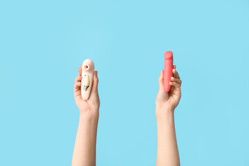 Female hands with vibrators on color background