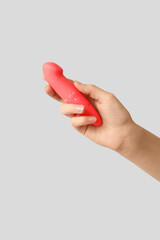 Female hand with vibrator on grey background, closeup
