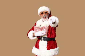 Santa Claus in 3D glasses with buckets of tasty popcorn on brown background