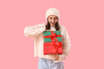 Young woman with Christmas presents on pink background