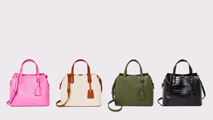 Four trendy colorful leather handbags on grey background.
