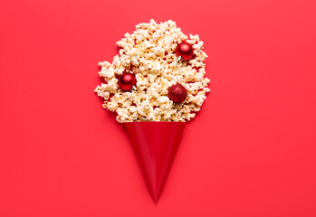 Popcorn with party hat and Christmas tree balls on red background