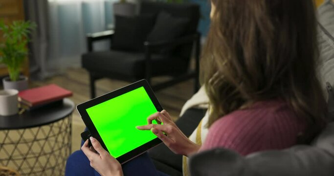 Woman could be an avid reader, engrossed in an e-book or digital magazine on the laptop. The green mockup screen suggests her access to a vast digital library.