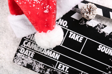 Movie clapper with Santa hat and pine cone on decorative snow