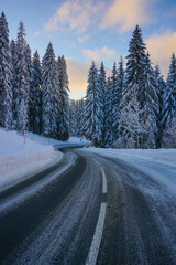 alpine road in the mountains with snow covered trees in winter