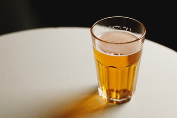 A refreshing pint of beer on a white table with a dark backdrop