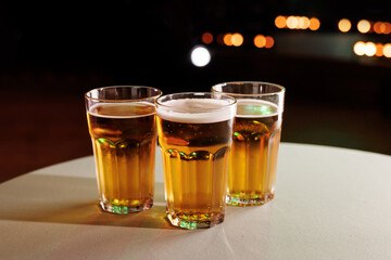 A trio of beer glasses on a white table.