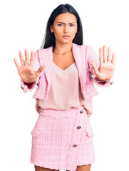 Young beautiful latin girl wearing business clothes doing stop gesture with hands palms, angry and frustration expression