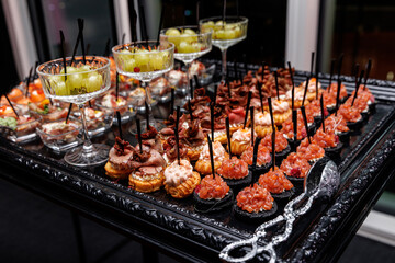 A black tray with a silver rim holding a selection of appetizers and finger foods