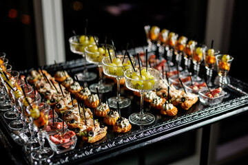 A black tray with a silver rim holding a selection of appetizers and finger foods - obrazy, fototapety, plakaty