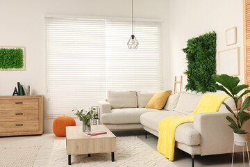 Green artificial plant wall panel and comfortable furniture in cozy living room. Interior design