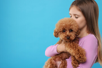 Little child with cute puppy on light blue background, space for text. Lovely pet