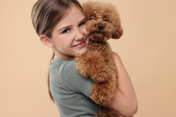 Little child with cute puppy on beige background. Lovely pet