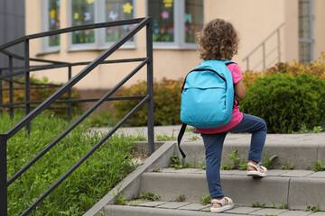 Little girl walking to kindergarten outdoors, back view. Space for text
