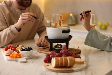 Couple enjoying fondue during romantic date in kitchen, closeup