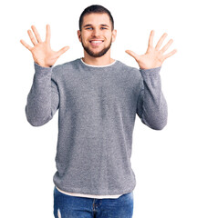 Young handsome man wearing casual sweater showing and pointing up with fingers number ten while smiling confident and happy.