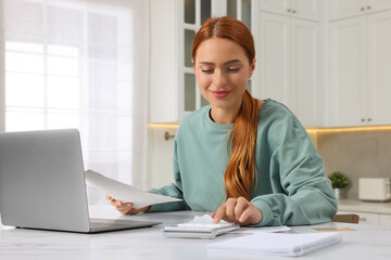 Woman calculating taxes at table in kitchen