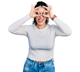 Young hispanic woman wearing casual clothes doing ok gesture like binoculars sticking tongue out, eyes looking through fingers. crazy expression.