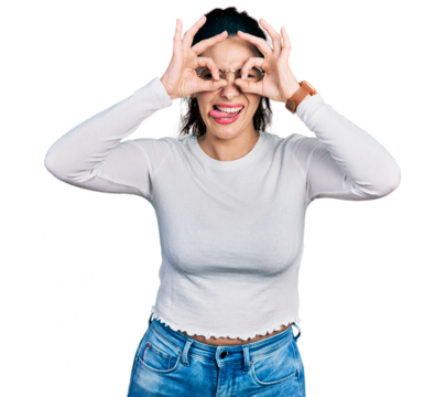 Young hispanic woman wearing casual clothes doing ok gesture like binoculars sticking tongue out, eyes looking through fingers. crazy expression.