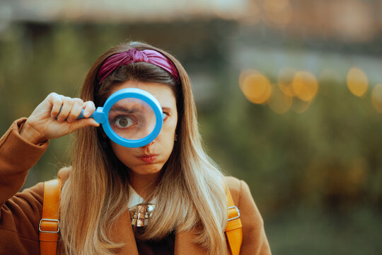 Funny Curious Woman Looking Through a Magnifying Glass. Critical perfectionist girl inspecting the quality of a work

