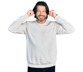 Middle age caucasian man wearing casual clothes smiling pulling ears with fingers, funny gesture....