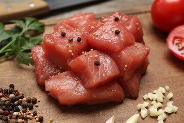 Cooking delicious goulash. Raw beef meat with different spices on wooden table, closeup