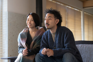 リビングでくつろぐ若い夫婦 秋冬 自宅でテレビや動画を見る秋冬
