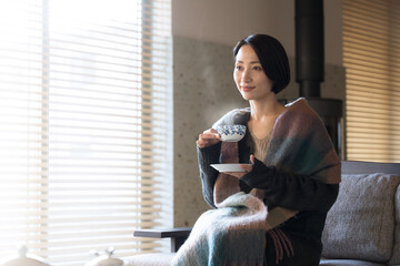 温かい飲み物を飲むストールを羽織った美しい女性  秋冬