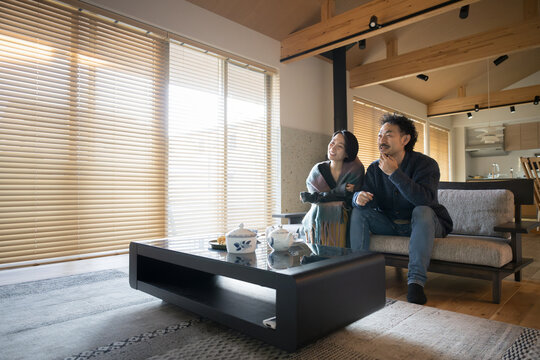 Young Couple Relaxing In The Living Room Autumn/Winter Enjoying TV And Videos At Home Copy Space On The Left