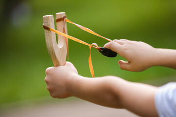 Little girl playing with slingshot outdoors, closeup