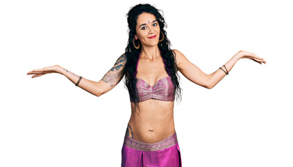 Young indian woman wearing belly dancer costume clueless and confused expression with arms and hands raised. doubt concept.